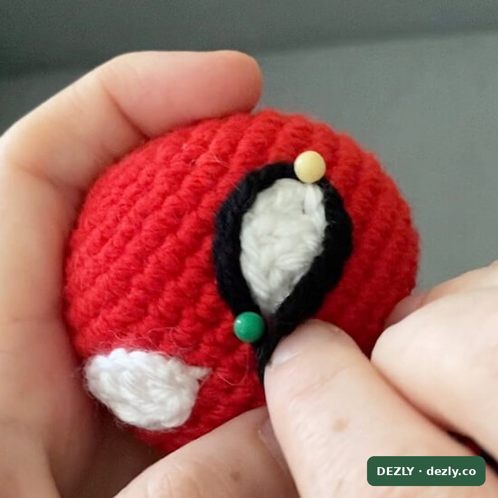 Cosiendo el contorno de cadeneta negra alrededor de un ojo a crochet sujeto con alfileres en la cabeza